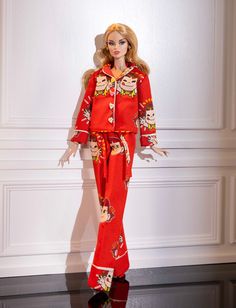 a barbie doll wearing a red pajamas and hat with her hands on her hips, standing in front of a white wall