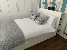 a white bed sitting in a bedroom on top of a hard wood floor