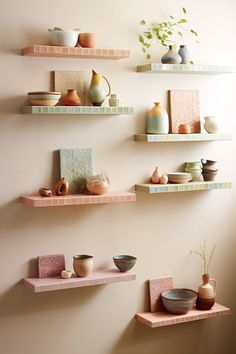 three shelves with vases, bowls and plates on them are lined up against the wall