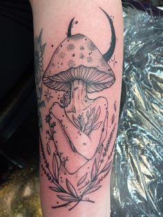 a black and white photo of a mushroom tattoo on the left arm with leaves around it