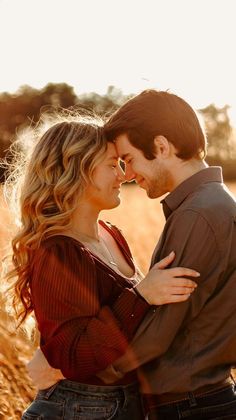 a young man and woman embracing each other in the middle of a wheat field at sunset