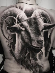 a woman's back with a goat tattoo on it