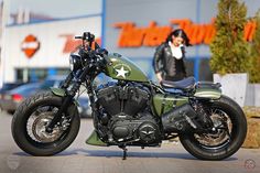 a green and black motorcycle parked in front of a building with a woman standing behind it