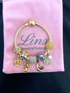 a pink velvet bag with gold charms on it and a ring in the middle that says lina jewelry company