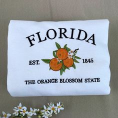 an orange blossom state embroidered on a white pillow case with flowers in the foreground