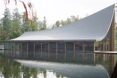 a large building sitting on top of a body of water next to a forest filled with trees