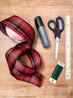 scissors, tape and other crafting supplies laid out on a wooden surface next to a ruler