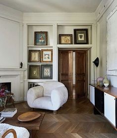 a living room filled with white furniture and pictures on the wall above it's fireplace