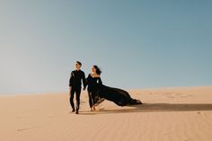 a man and woman are walking in the sand