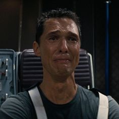 a man standing in front of a luggage bag and looking at the camera with an intense look on his face