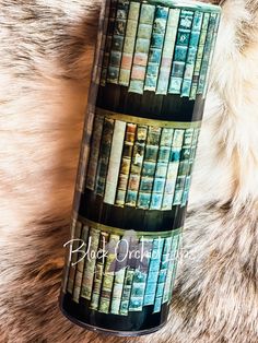 a coffee cup with books on it sitting on a furry surface next to a fur rug