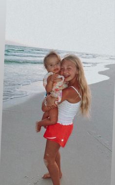 a woman holding a baby on the beach