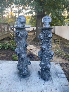 two metal sculptures sitting on top of a cement slab