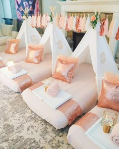 pink and gold bedding in front of a fireplace with pillows on the floor next to it