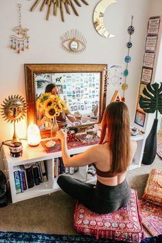 a woman sitting on the floor in front of a mirror