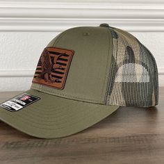 American Flag Eagle Patriotic Leather Patch Hat Green/Camo. Specifications: 🧢 Richardson original 112 trucker; adjustable for the perfect fit 🎩 60/40 cotton/polyester blend for comfort 📏 One size fits most 🏷️ Expertly laser engraved leatherette patch design 📦 Ships in 2 to 3 business days from our Orlando Studio Care Instructions: 🚫 Do not wash; spot clean only Please Note: 🌈 Colors may vary from photos based on your viewing screen. This funny hat is a unique and entertaining gift for fathers, embracing their dual role with humor. Brown Military Style Trucker Hat, Brown Military Trucker Hat, Adjustable Camouflage Trucker Snapback Hat, Adjustable Khaki Flat Bill Hat, Adjustable Flat Bill Hat In Khaki, Military Style Brown Baseball Cap With Flat Bill, Military Style Flat Brim Trucker Hat For Outdoor, Adjustable Khaki Snapback Hat With Flat Bill, Military Style Adjustable Flat Brim Baseball Cap