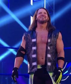 a man with long hair and no shirt on standing in front of a blue background