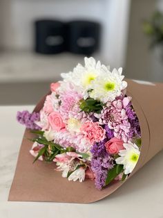 a bouquet of flowers sitting on top of a brown paper bag with white and pink flowers