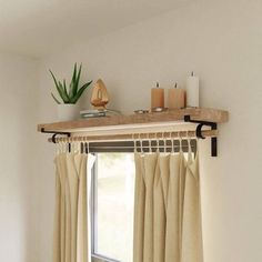 an open window with curtains and candles on the ledge above it, next to a potted plant