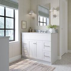 a white bathroom with two sinks and a large mirror on the wall next to a window