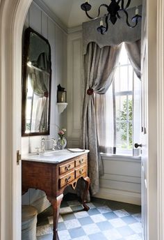 a bathroom with a checkered tile floor and white walls, along with an antique vanity