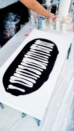 a person is painting on a large piece of white paper with black paint and brush