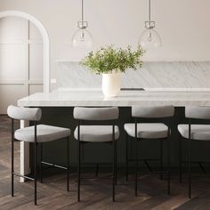 a kitchen with marble counter tops and stools next to a plant in a vase