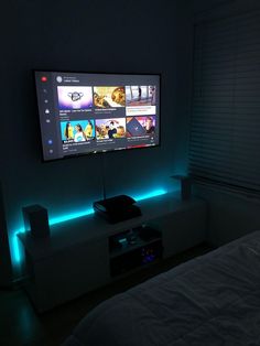 a flat screen tv mounted to the side of a wall in a dark room with blue lights