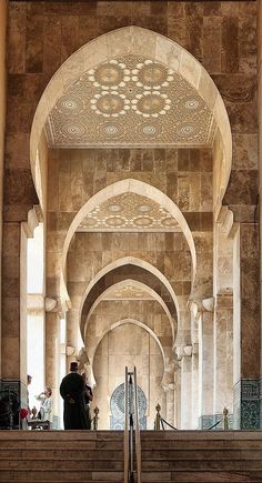 the inside of an ornate building with stone arches and pillars, along with people walking up stairs