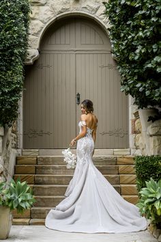 a woman in a wedding dress is standing on the steps outside an entrance to a building