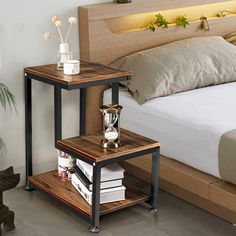 a bed sitting next to a night stand on top of a wooden floor