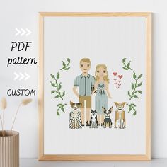 a cross stitch picture with a couple and their dogs in front of the frame, next to a potted plant