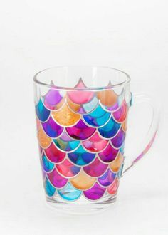 a glass mug with colorful fish scales on the bottom and sides, in front of a white background