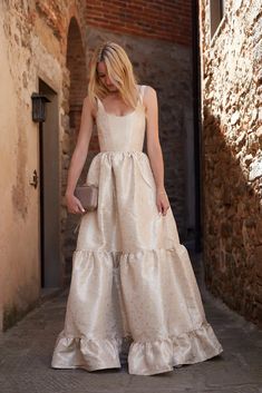 a woman in a white dress is walking down the street