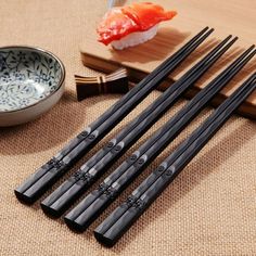 five chopsticks and some sushi on a table