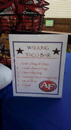 a sign that is sitting on top of a blue table cloth with food in the background