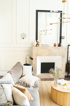 a living room filled with furniture and a fire place in front of a large mirror