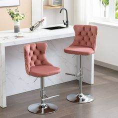 two pink barstools sitting in front of a counter