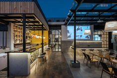 an empty restaurant with tables and chairs in the center, lit up at night time