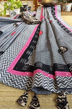 This exquisite handloom saree exudes a sense of understated elegance and contemporary charm. Crafted from pure, lightweight cotton, it presents a harmonious blend of colors and intricate detailing, making it a versatile choice for various occasions, particularly ideal for the upcoming festive season. The dominant shade of this saree is a steel grey, reminiscent of sophistication and modernity. The body of the saree is adorned with delicate zari checks, which glisten with a subtle opulence. What Multicolor Cotton Blouse Piece With Motifs, Cotton Dupatta With Printed Border, Cotton Blouse Piece With Kalamkari Print For Festivals, Multicolor Cotton Blouse Piece With Traditional Patterns, Traditional Cotton Blouse Piece With Printed Motifs, Festive Cotton Handloom Blouse Piece, Cotton Saree With Traditional Patterns, Unstitched Cotton Fabric For Festivals, Cotton Block Print Blouse For Festivals