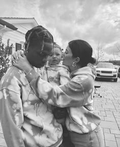 a black and white photo of a man holding a baby in his arms while standing next to a woman