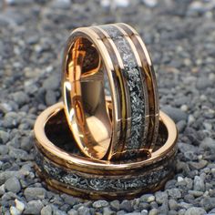 two gold wedding bands with black and white marble inlays on top of each other