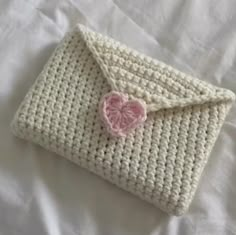 a white crocheted purse with a pink heart on the front and bottom flap