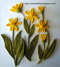 some yellow flowers are sitting on a white surface and one is cut out to look like leaves