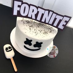 a white cake sitting on top of a black table next to a popsicle and sign