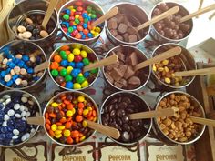 a table topped with lots of different types of candies and ice creams next to wooden spoons