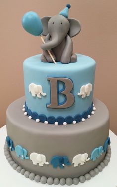 a blue and gray cake with an elephant on top that says b is for baby