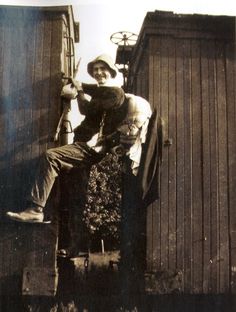 an old black and white photo of a man sitting on the back of a chair