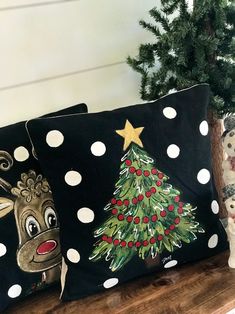 three decorative christmas pillows sitting on top of a wooden shelf next to a potted tree