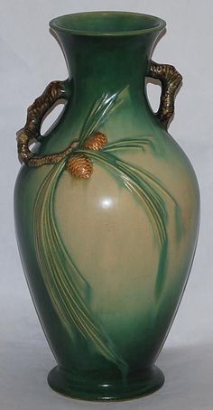 a green and white vase with gold decorations on the top, sitting against a white background